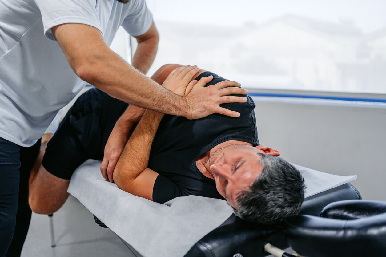 Dallas sports chiropractor performing a spinal adjustment on a male athlete on a treatment table with the Dallas skyline visible through a window