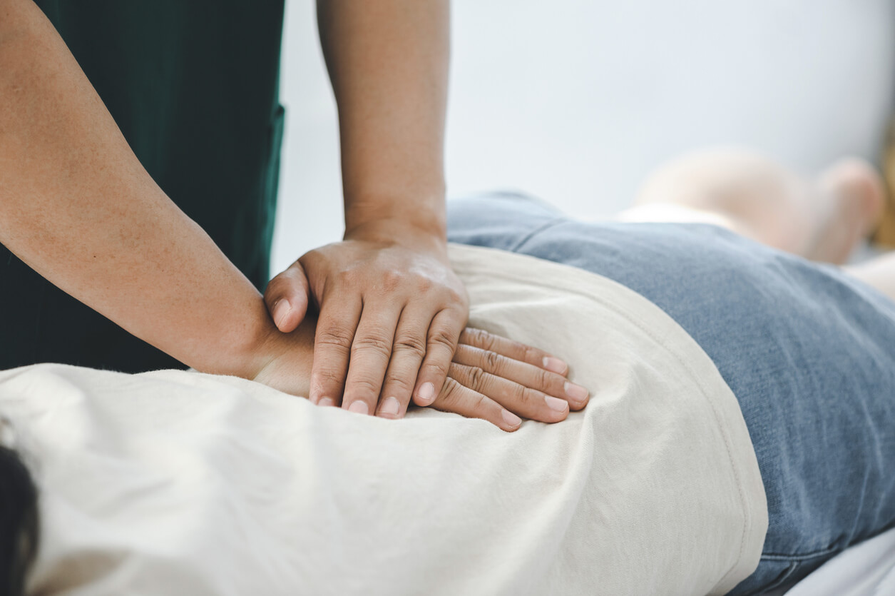 Dallas chiropractor performing a gentle lower back adjustment on a patient in a modern, well-lit medical clinic